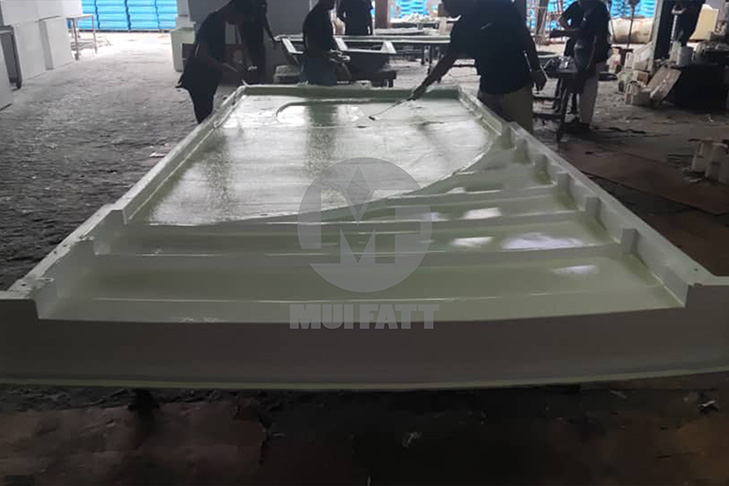 Workers applying fiberglass resin using hand lay-up method during the production of custom FRP signage boards