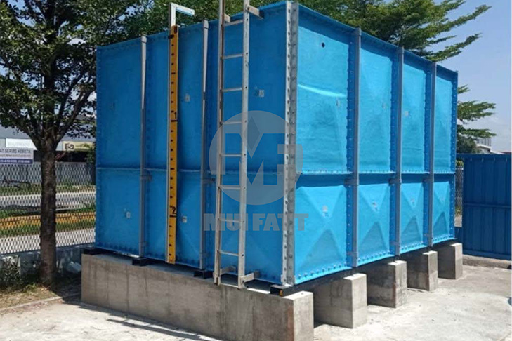 Blue FRP sectional water tank mounted on concrete plinths with ladder and water level, ensuring structural support and easy maintenance access
