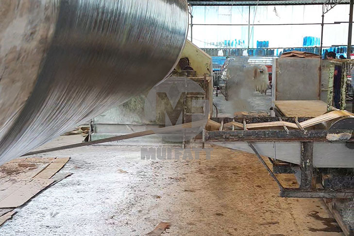 Automated filament winding machine applying resin-coated fibers to a rotating mandrel for cylindrical FRP tank manufacturing.