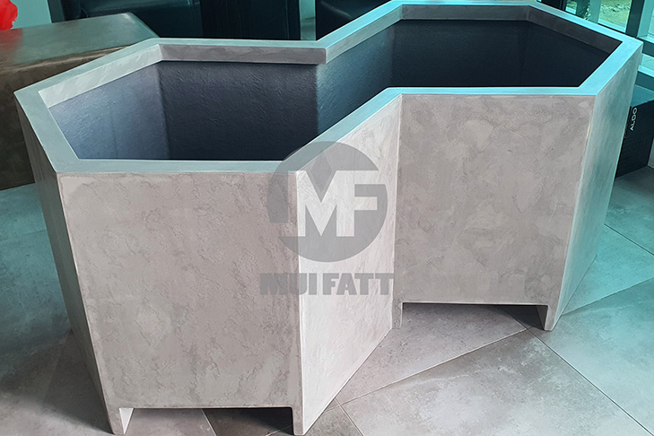 Custom-designed hexagonal FRP planter box with textured concrete look, part of Tuta Courtyard landscaping project