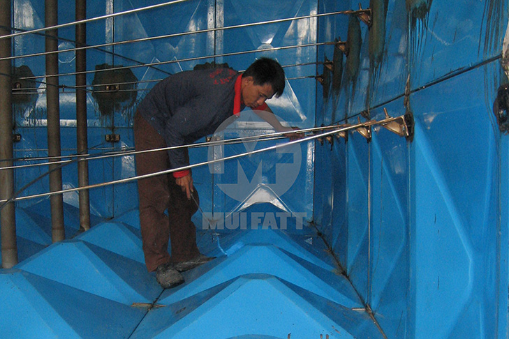 Technician applying repair resin to the inner surface of an FRP closed top tank