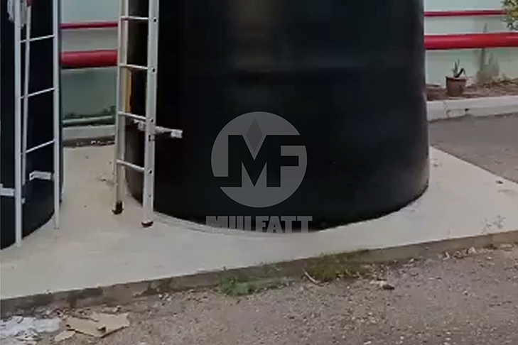 A large vertical PE water storage tank placed on a concrete slab outdoors, providing a level and secure foundation for the tank.