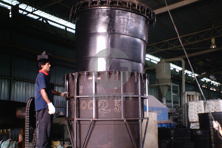 Technician at Mui Fatt removing a large black PE water tank from its rotational molding steel mold after cooling phase.