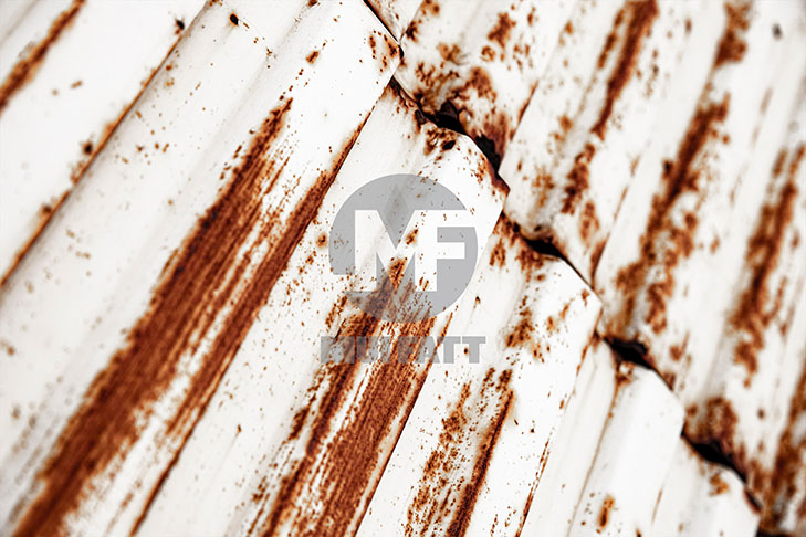 Close-up of heavily rusted white metal roof panels showing long-term corrosion damage in harsh environments.