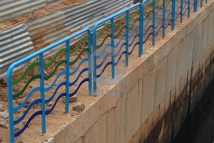 Side angle showing wave-pattern FRP handrails securely mounted to a concrete canal embankment in Kuantan, Malaysia.