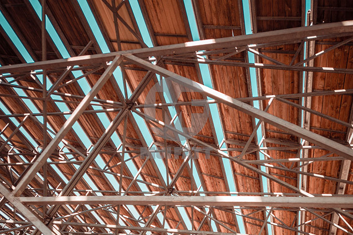 Interior view of steel truss system and roofing sheets exposed to moisture and corrosive air, highlighting potential rust issues in industrial buildings.