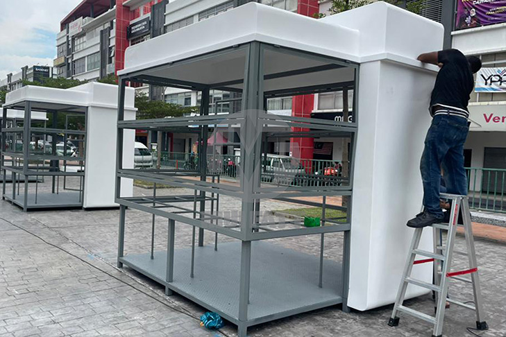 Onsite technician fixing FRP panels onto the kiosk frame during the MyKiosk project installation phase