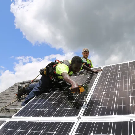 Worker installing solar panel on rooftop without roof walkways